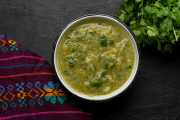 Mexican piquant green sauce with cilantro and onion on dark background