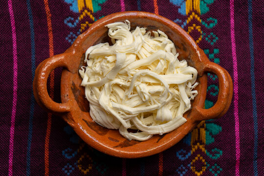 Shredded Oaxaca cheese also called quesillo on rustic background. Mexican food