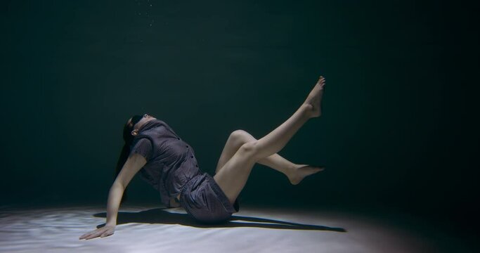 Waking up from sleep. Young beautiful woman in pyjamas, eye mask rises up from under water and dreaming slow motion.