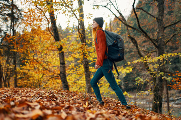 woman traveler with backpack walking in the park in autumn in nature side view