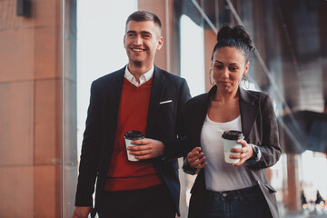 Business man and business woman talking and holding luggage traveling on a business trip, carrying fresh coffee in their hands.Business concept