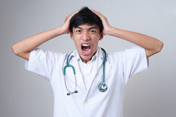 Young Asian doctor male screaming hold his head