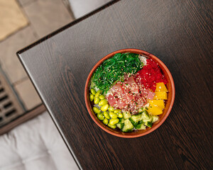 Hawaiian tuna poke bowl with vegetables on wooden table