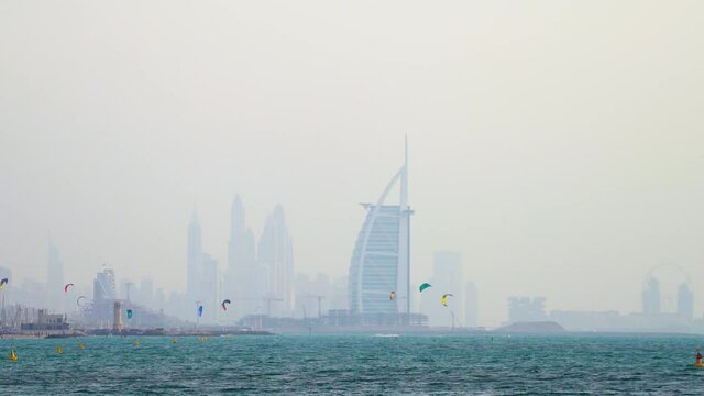 Kite Surfing On Dubai Beach With Burj Al Arab Hotel In Cityscape Background At United Arab Emirates. - Wide Shot