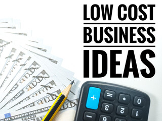 Business concept.Text LOW COST BUSINESS IDEAS with calculator,pencil and banknote on white background.