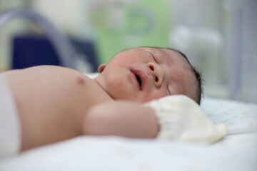 Obraz na płótnie Canvas Asian newborn baby in the delivery room at hospital. In the newborn incubator is A medical device used to regulate the temperature of a newborn baby to be healthy according to the criteria
