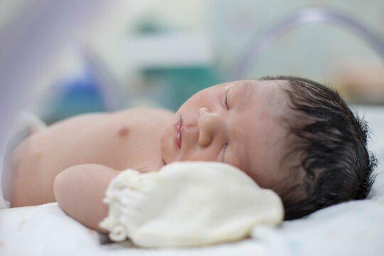 Asian newborn baby in the delivery room at hospital. In the newborn incubator is A medical device used to regulate the temperature of a newborn baby to be healthy according to the criteria