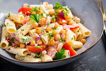 Vegetarian vegetable pasta. Pasta rigatoni with tomato, red onion, parsley and fried chickpeas with nut sauce. Vegan food.