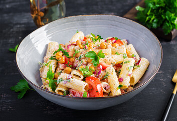 Vegetarian vegetable pasta. Pasta rigatoni with tomato, red onion, parsley and fried chickpeas with nut sauce. Vegan food.