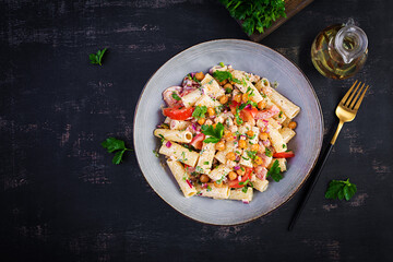 Vegetarian vegetable pasta. Pasta rigatoni with tomato, red onion, parsley and fried chickpeas with nut sauce. Vegan food. Top view, overhead