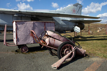 Aerodrome maintenance technique. Old airfield equipment sits next to an old jet fighter.