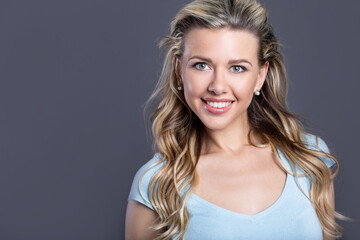 Beautiful blonde with curly hair on a gray background.