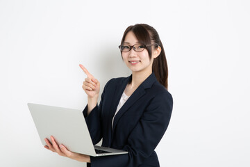 パソコンを持って指差ししているメガネのビジネスウーマン