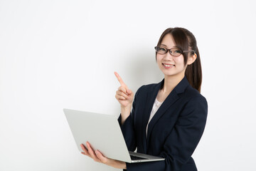パソコンを持って指差ししているメガネのビジネスウーマン