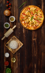 Banner of tray of homemade seafood pizza with tomatoes, fried onion, oregano, rolling pin, dough, olive oil, powder, ketchup, bell peppers located in row below the wooden background with copy space.