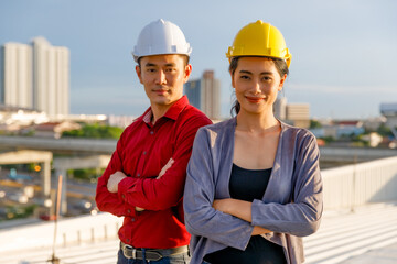 Confident Asian contractors looking at camera on roof of building