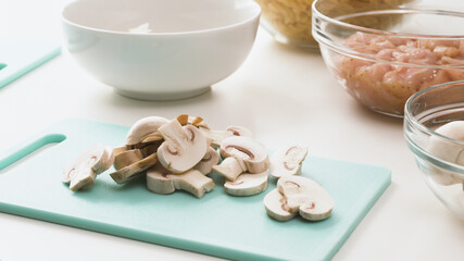 Chopped mushrooms on cutting board. Pasta with chicken and mushrooms recipe. Raw ingredients close up on kitchen table.