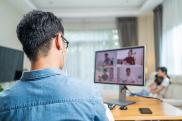 Rear view shot of Asian father working from home by video conference.	