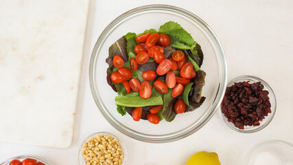 Lettuce salad with fresh cherry tomatoes, dry cranberries, nuts, and honey mustard salad dressing recipe. Close up view from above, copy space