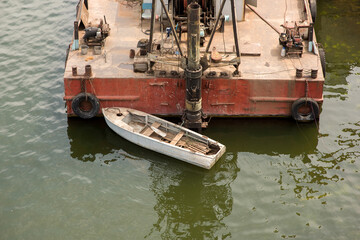Fototapeta na wymiar Aluminum boat moored to a floating barge on the river bank