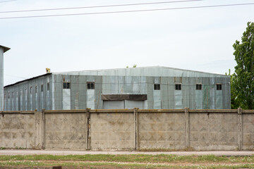 Fototapeta na wymiar Warehouse building behind a concrete fence