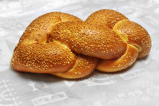 Challah - Jewish bread in Israel and at world. Inscriptions on the white tablecloth in Hebrew: Shabbat Shalom - Jewish and Israeli greetings