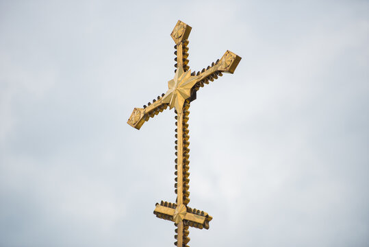 Large gilded church cross against a background of gray clouds