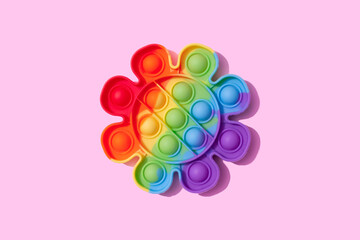 Rainbow pop it fidget toy on pink background. Push bubble fidget sensory toy - washable and reusable stress relief toy. Antistress toy for children or adult. Mental health concept, selective focus