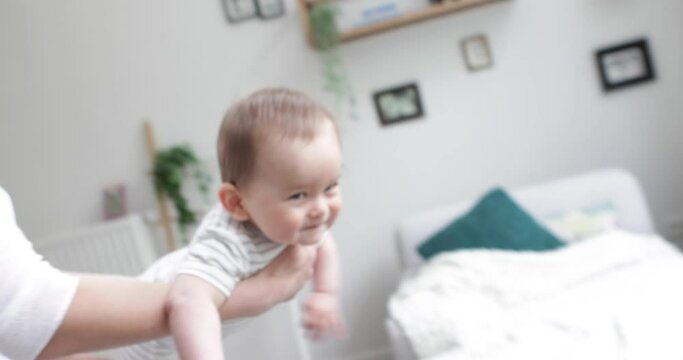 baby boy enjoying fling game in mothers  arms, 50fps handheld camera.