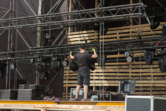 worker assembles the lighting equipment of the mobile stage