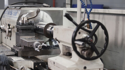 Turning lathe in action. Facing operation of metal blank on turning machine with cutting tool. Old turning lathe machine in turning workshop. Operator machining high precision mold part by cnc lathe