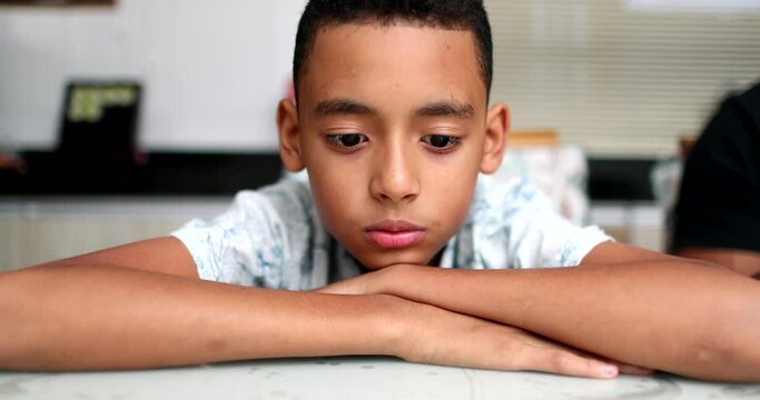 Pensive sad African descent child. Contemplative kid looking down