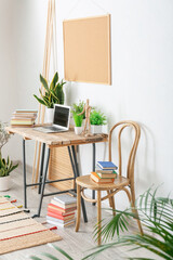 Comfortable workplace with books and houseplants in interior of room