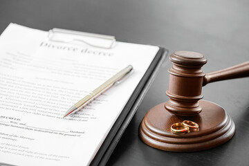 Judge's gavel, rings and divorce decree on dark background