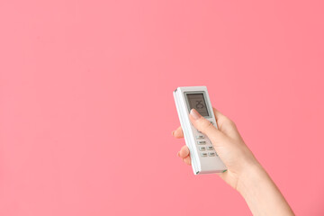 Young woman with air conditioner remote control on color background