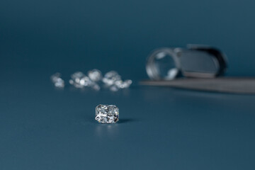 Cut diamond in hand close up with jewelry tools and scattering of different diamonds in background,...