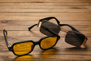 Different modern sunglasses on wooden background, closeup