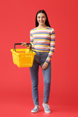 Naklejka premium Young woman with shopping basket on color background