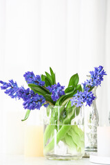 Vase with beautiful hyacinth flowers and burning candles on table