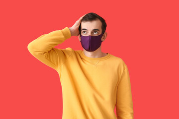 Young man wearing medical mask on color background