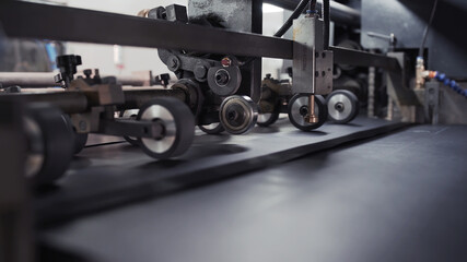 Modern automatic conveyor line for the production of package. Cardboard manufacturing layering rollers roll industrial industry printing packaging material closeup. Enterprise for production package