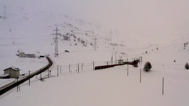 Aerial bird's eye view of Hogwarts express at iron track during getaway travelling for visiting picturesque nature environment in Scandinavia, drone camera flying over snowy mountains with railway