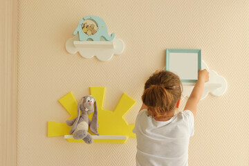 Stylish and modern Interior design. room. girl happy lifestyle puts a photo frame on a shelf...