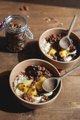 Oatmeal with pineapple, banana and chocolate granola in beige plates on a brown wooden table. A hearty healthy breakfast. A place for text.