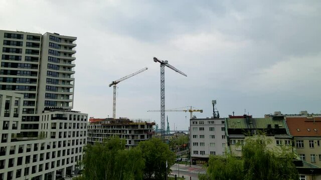 Aerial view of cranes on construction site in polish residential area with blocks and apartments during cloudy day