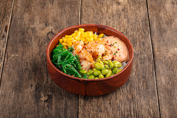 Hawaiian shrimp poke bowl with vegetables on wooden background
