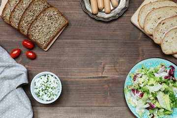 Healthy salad, cottage cheese, sausages and bread on a wooden table.