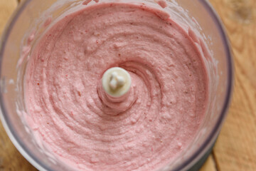 Close up of Mixed strawberries with yoghurt and banana in blender cup. Smoothie preparation process, top view. mixing ingredients for strawberry milkshake in glass blender concept.