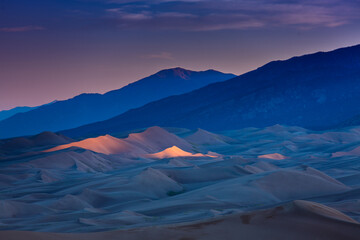 Dramatic landscape of last light hitting the peaks of the Colorado Sand Dunes under a colorful dusk skies.