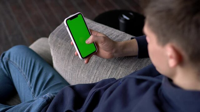 Cropped male blogger using blank smartphone gadget with mockup green touchscreen for your website, man holding modern blank cellular technology with copy space area for text advertising